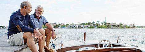 Zwei Herren sitzen auf einem Bootssteg am See